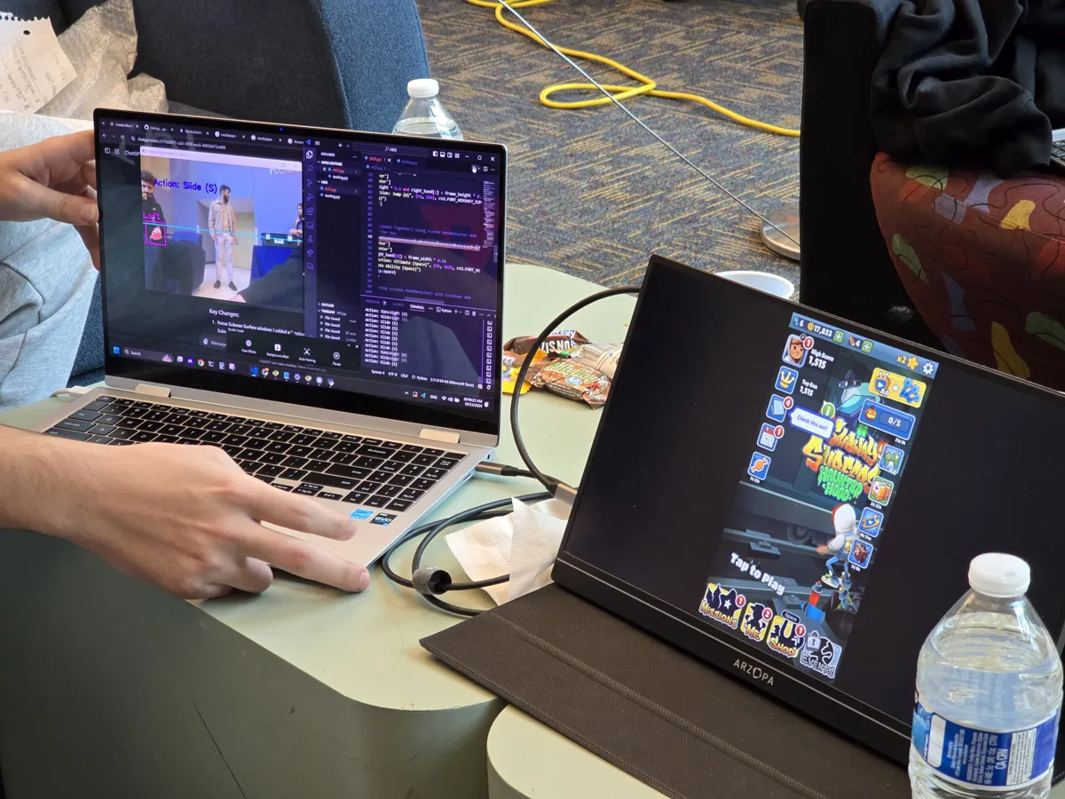 A laptop showing the webcam pose tracker next to a screen running Subway Surfers during playtesting